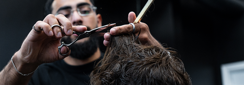 Barber at Montana Fades in Oakville trimming a male client’s hair with scissors and comb, styling a textured crop haircut—one of 2025’s top men’s grooming trends.