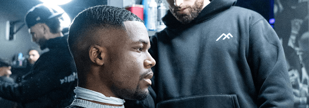 A barber at Montana Fades in Oakville, Ontario cutting a client’s hair into a clean fade, showcasing men’s 2025 fade haircut trends.