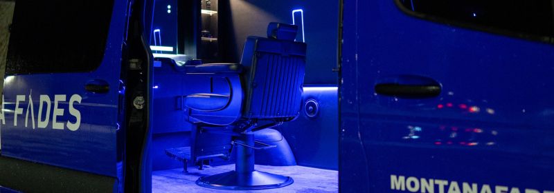 Interior of the Montana Fades Sprinter mobile barbershop in Oakville, showing a premium barber chair and clean, climate-controlled grooming studio lit by blue LED accents.